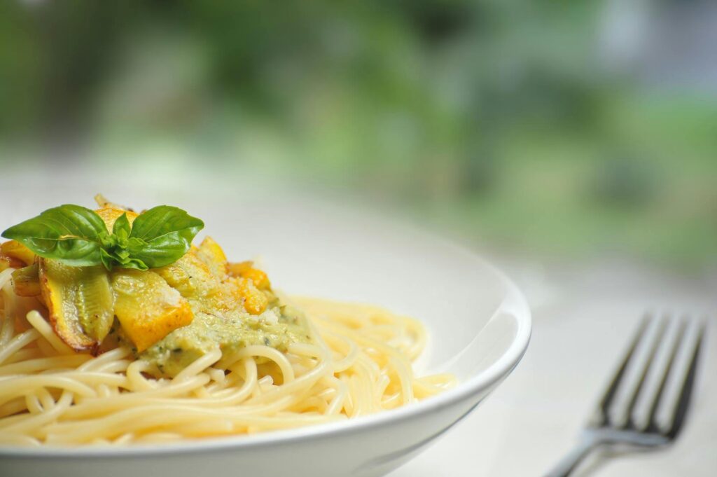 pexels-photo-64208-64208 Close-up of freshly made spaghetti topped with basil and creamy pesto sauce in a white dish.